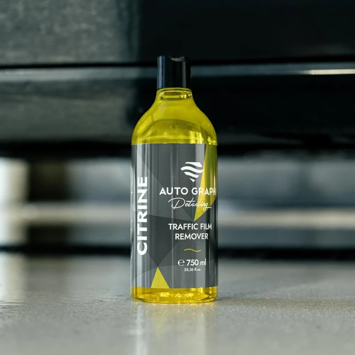 CITRINE Traffic Film Remover, butelka 750 ml stojąca na podłodze na tle rozmytego samochodu