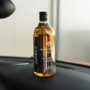 Butelka AMBER All Purpose Cleaner postawiona na desce rozdzielczej samochodu