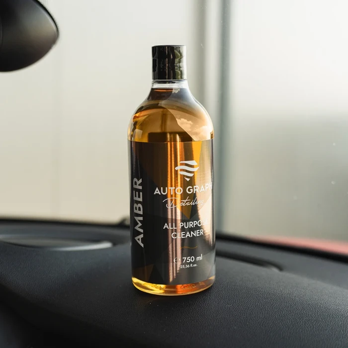 Butelka AMBER All Purpose Cleaner postawiona na desce rozdzielczej samochodu