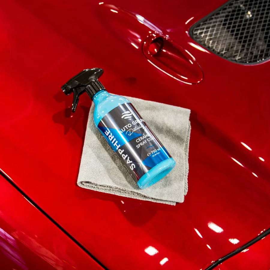 Butelka SAPPHIRE Ceramic Spray Coat leżąca na szarej mikrofibrze na czerwonej masce auta
