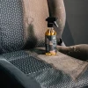 butelka z atomizerem SUNSTONE Fabric Cleaner na zaplamionym siedzeniu z materiałowej tapicerki